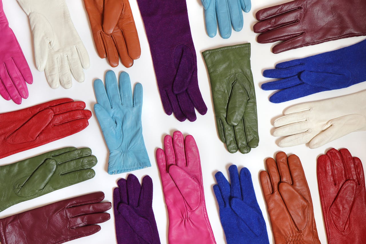 hero-img-01 A vibrant collection of assorted leather gloves arranged in a flat lay pattern.